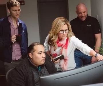 Bank employees solving a problem together on a computer.