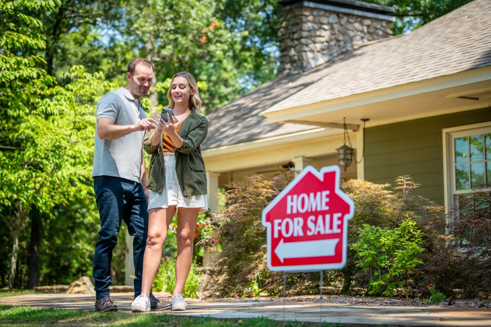 man and woman standing in front of a house for sale. 