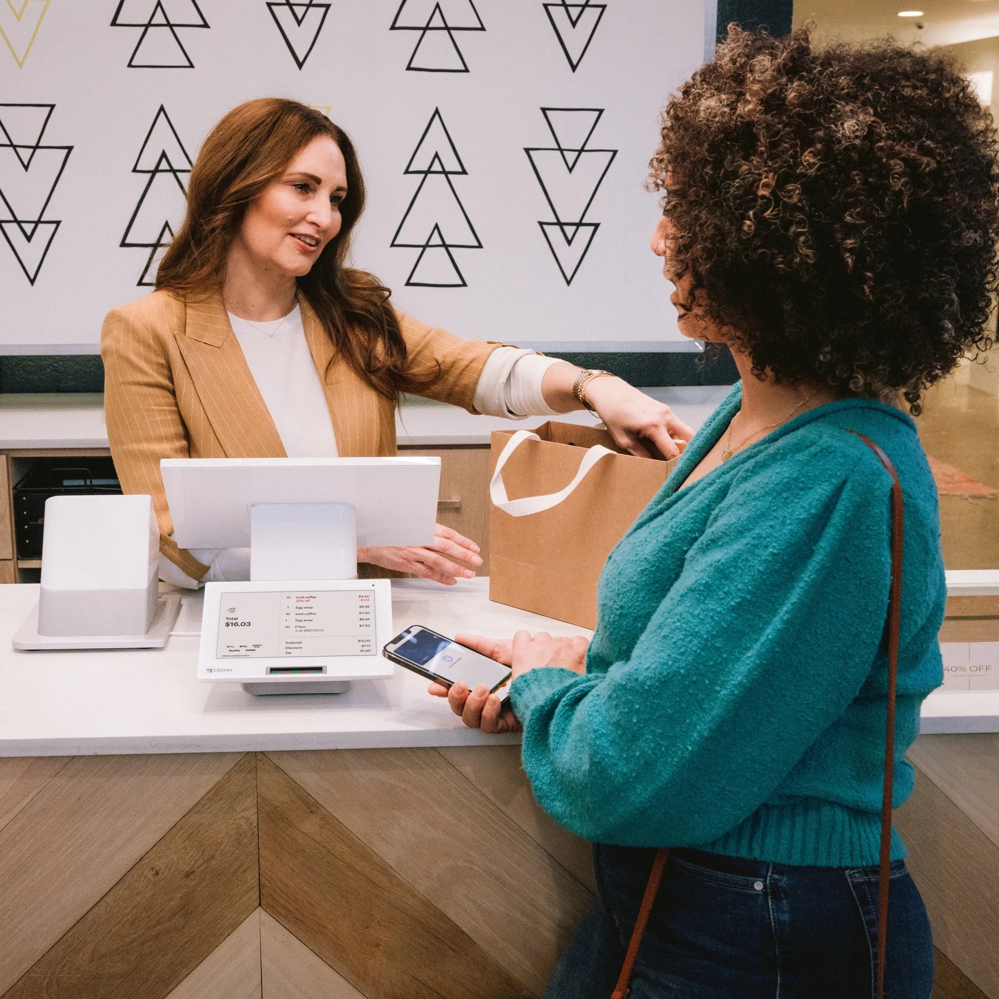 Saleswoman handing a clothing bag to another woman