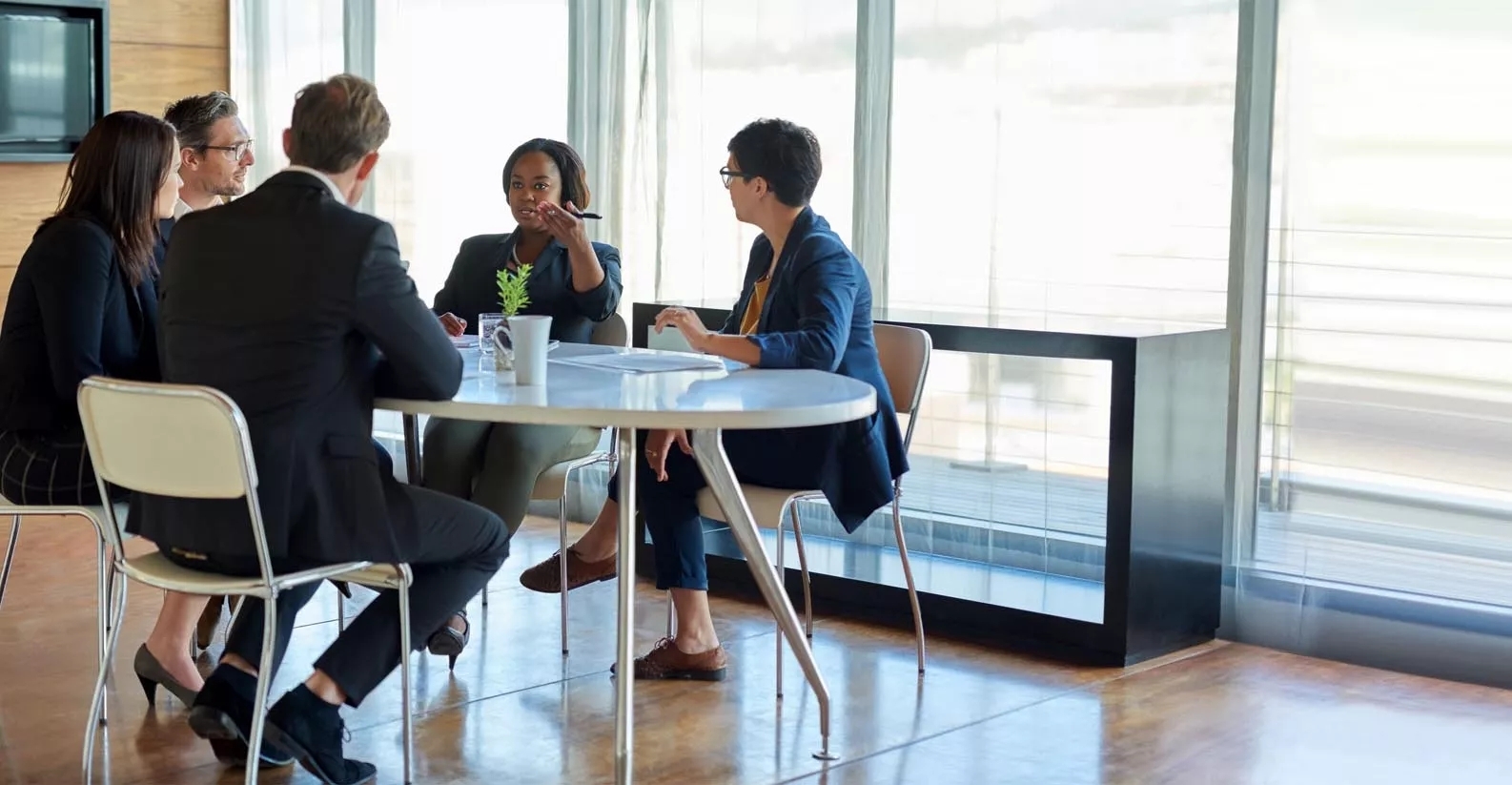 A team having seated discussion in a modern, well lit meeting room.