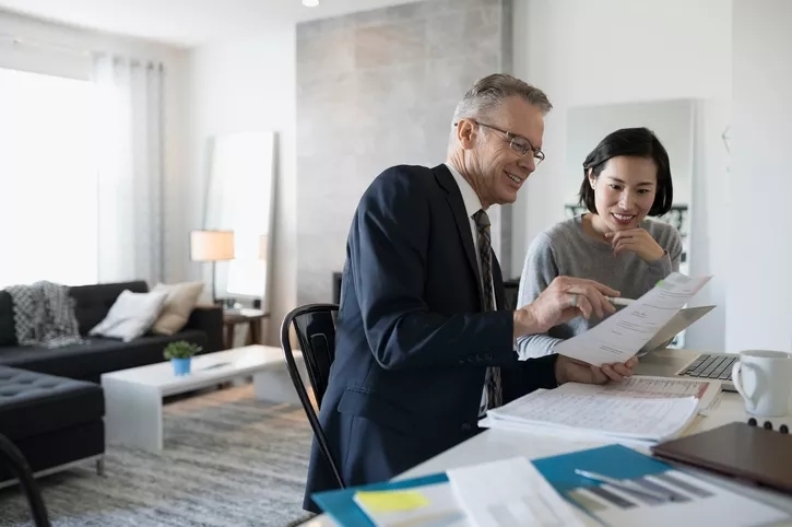 A man and woman looking over financial papers, gesturing with a pen.