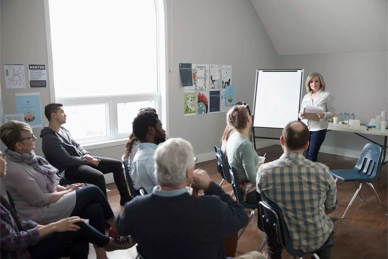 bunch of people having a meeting and a person speaking to the whole group