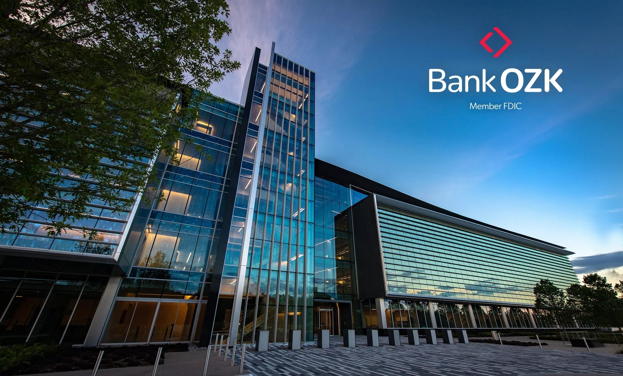 Bank OZK Headquarters building at dusk, with the Bank OZK Logo on the upper right.