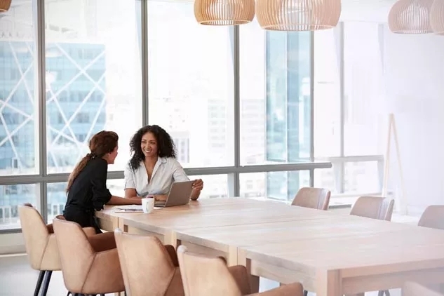 Two women sitting at a table having a meeting.