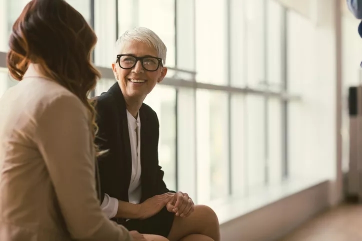 Businesswoman having a conversation while sitting on window sill.