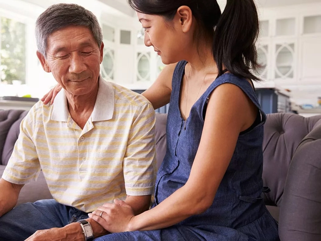 A woman and an older man sitting together on the couch.