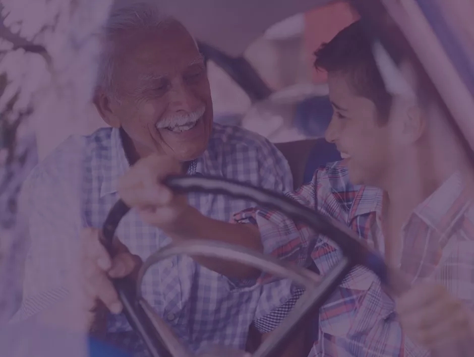 A grandfather teaching his grandson to drive a car.