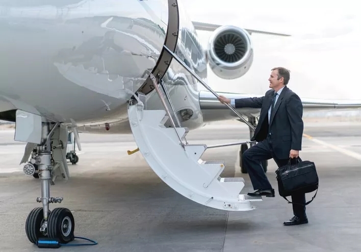 A businessman holding a briefcase stepping onto an aircraft's doorway stairs.