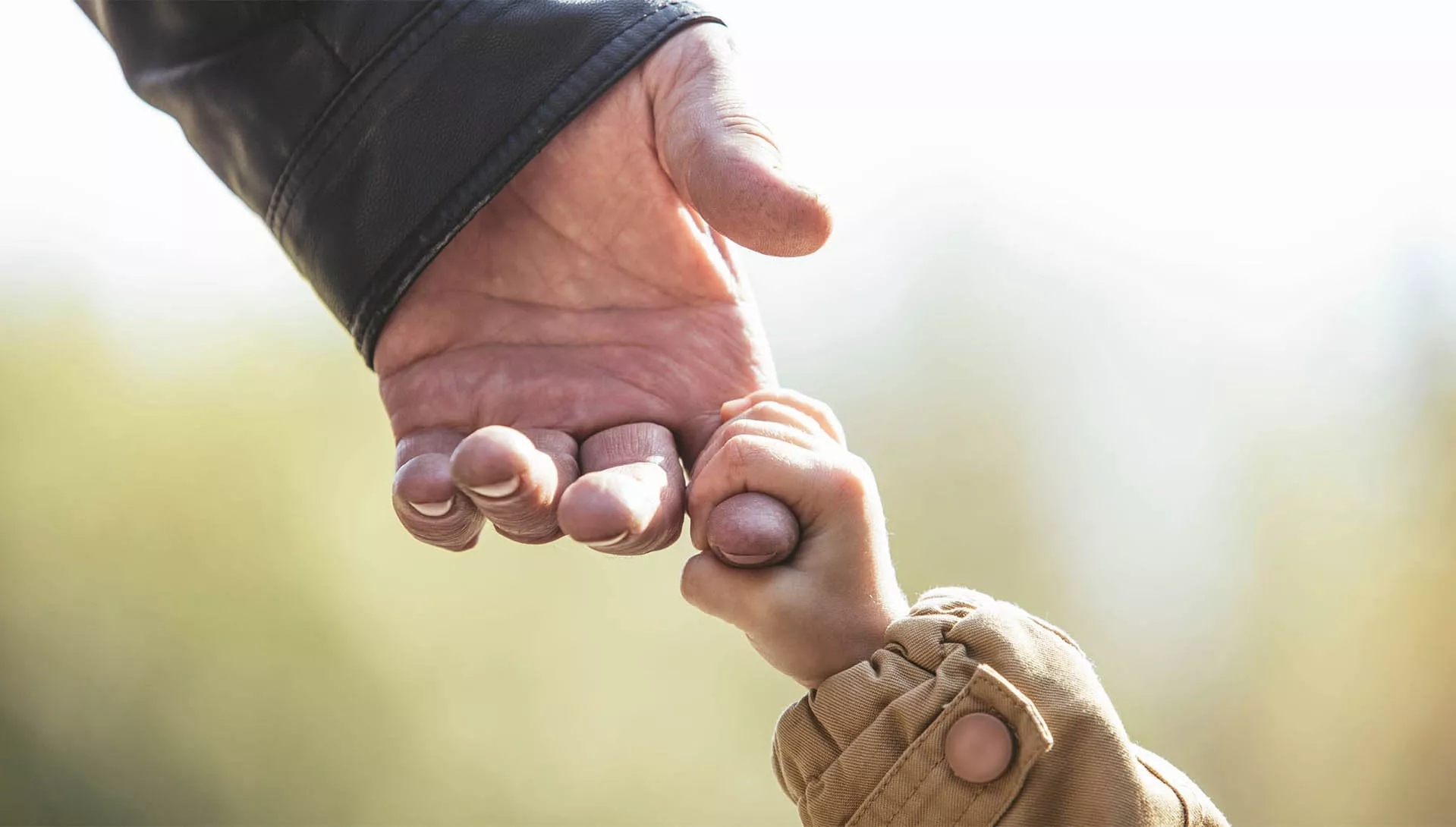 A child hand holding a man's index finger.