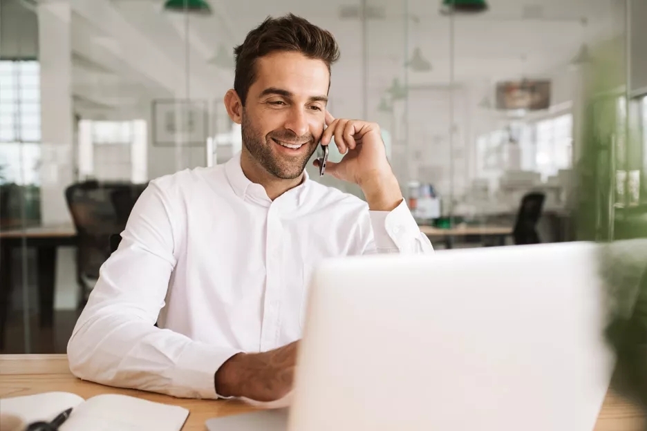 Man in front of laptop on phone