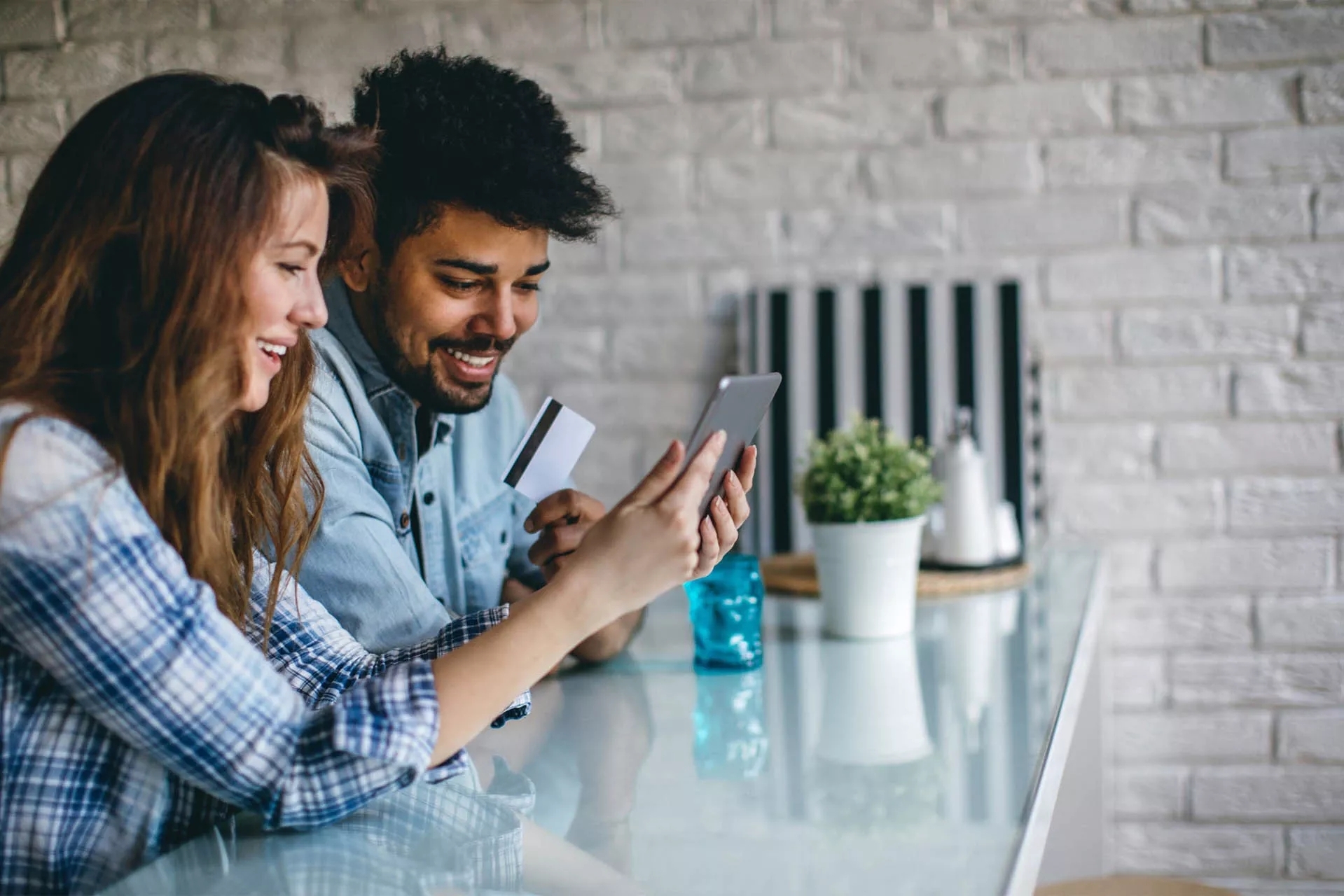 Two people holding and viewing a tablet, holding a credit card in another hand.