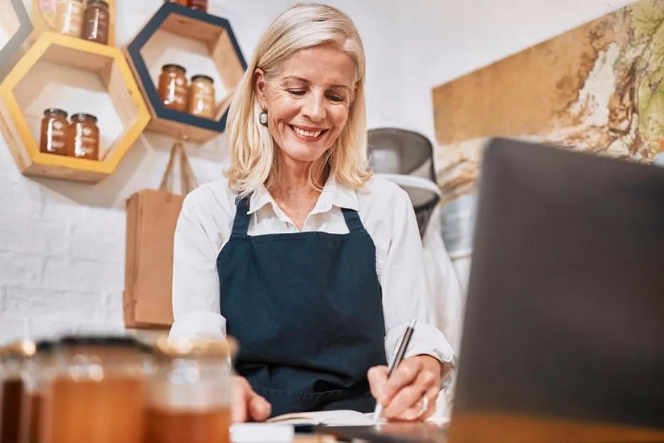 Business owner in front of laptop taking notes.